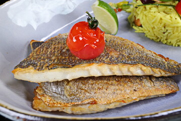 Fried dorado fish with lemon and tomato on a plate in a restaurant - 619607382