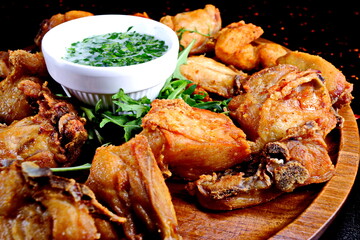 Fried chicken wings with sauce and arugula on wooden plate - 619607385
