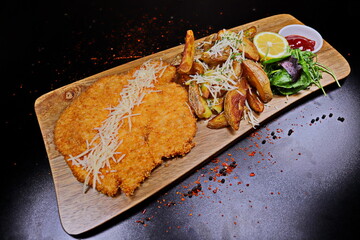 Pork schnitzel with french fries and sauce on a wooden board - 619607386