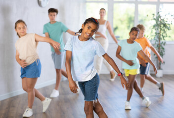 Active preteen boy practicing Hip-hop dance with other children and young trainer during dancing classes