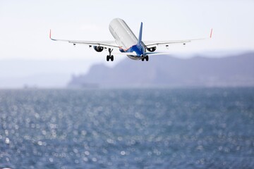 Fototapeta na wymiar Plane landing on the beautiful ocean beach background
