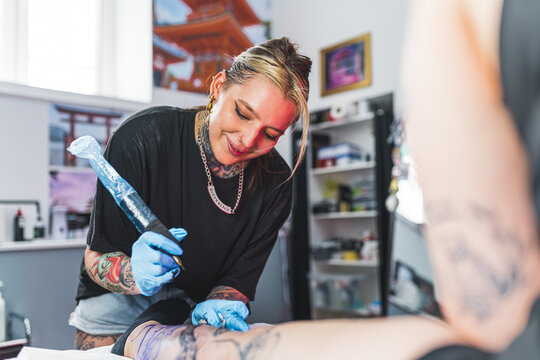 cheerful tattoo artist girl working in her studio, medium shot. High quality photo