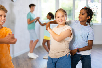 Active preteen children practicing Ballroom dances in pairs in training hall during dancing classes