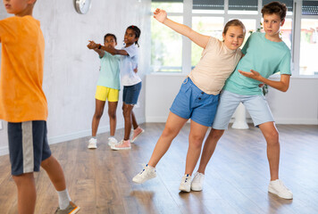 Light-skinned boy and girl dance in pairs and rehearse dance before performing on main floor. Classes for children workout in mini group gym
