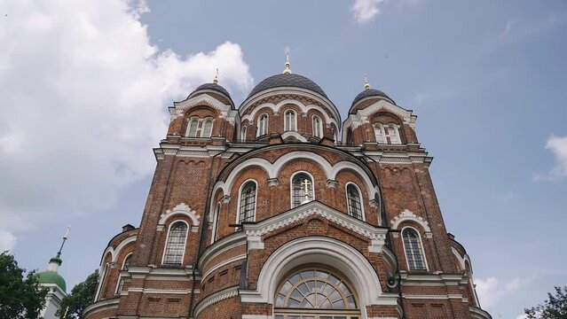 A large and beautiful Christian church stands against the background of the sky and clouds. The temple was made of red brick