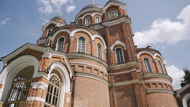 A monumental Christian church made of red brick rises against the sky. Shooting a religious building in motion