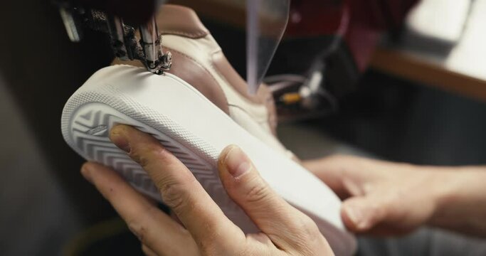 Close-up shot: stitching the sole and upper of a shoe on a special shoe-making machine in a textile factory