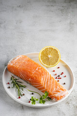 Fresh raw salmon fillet with ingredients for preparation.