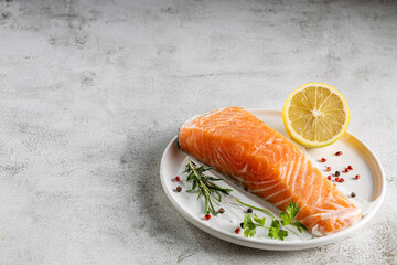 Fresh raw salmon fillet with ingredients for preparation.