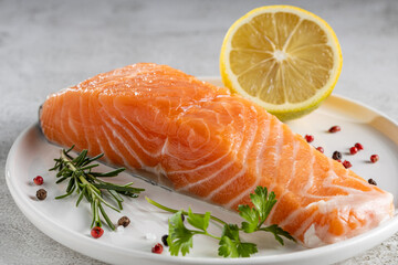 Fresh raw salmon fillet with ingredients for preparation.