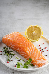 Fresh raw salmon fillet with ingredients for preparation.