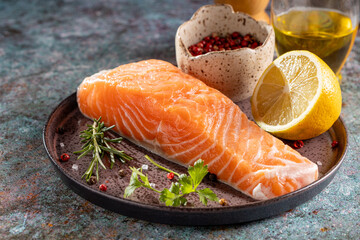 Fresh raw salmon fillet with ingredients for preparation.