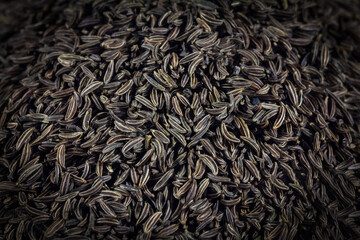 Selective blur on a macro shot pile of dried cumin seeds on display in backgroun. Cumin, also...