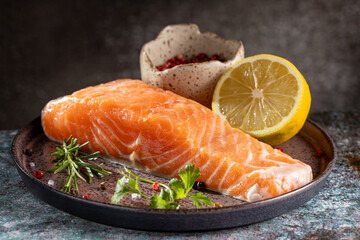 Fresh raw salmon fillet with ingredients for preparation.
