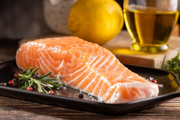 Fresh raw salmon fillet with ingredients for preparation.