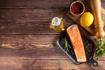 Fresh raw salmon fillet with ingredients for preparation.