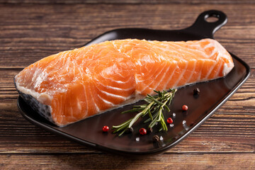 Fresh raw salmon fillet with ingredients for preparation.