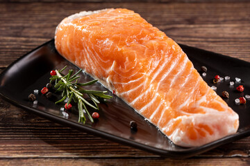 Fresh raw salmon fillet with ingredients for preparation.