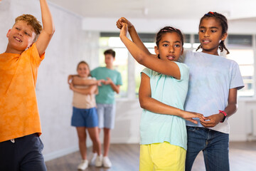 Cute smiling tweens, african american girl and boy learning to dance slow ballroom dances in pair...