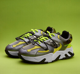 Stylish Women's metallic grey sport sneakers on green background