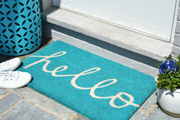Aqua teal hello welcome mat on a front porch in the summer