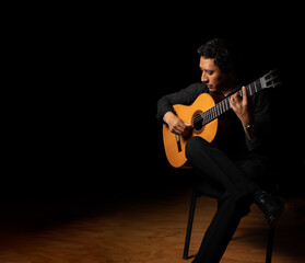 hispanic man playing guitar, guitarist on a black background studio shot, latin professional guitar...