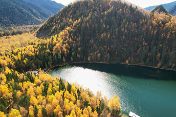  Emerald lake among the forest and mountains in autumn. Aerial view. Beautiful landscape.