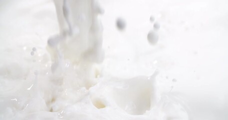 Close-up slow motion shot pouring fresh milk stream and splashing, milk cream splash