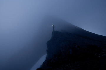 Hiker with headlamp in dense fog on mounain ride