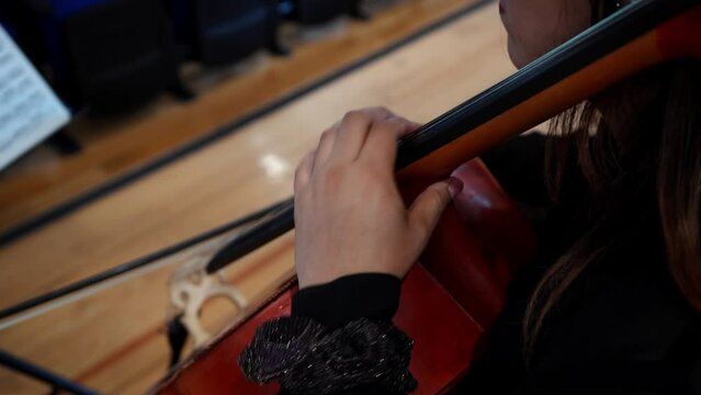 top view closeup on the hand of a hispanic woman playing cello, latin violoncellist performing a classical music piece, high angle