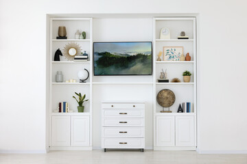 Interior design. Stylish tv area, chest of drawers and shelves with accessories indoors