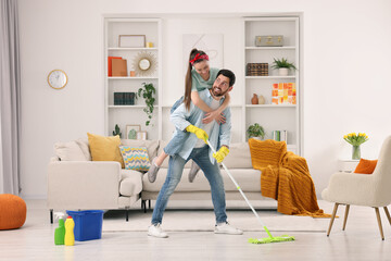 Spring cleaning. Couple having fun while tidying up living room