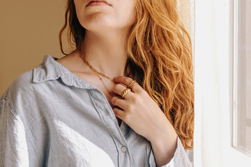 Close-up of unrecognizable woman touching her elegant necklace, natural light