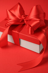 Beautiful gift box with bow on red background, closeup