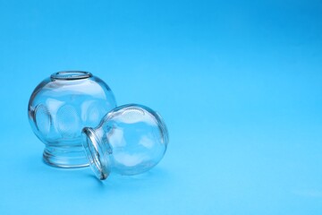 Glass cups on light blue background, space for text. Cupping therapy