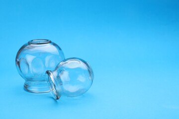 Glass cups on light blue background, space for text. Cupping therapy