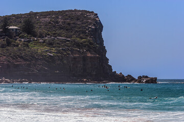 Surfers in the water near a headland