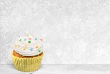 Delicious sweet cupcake with cream on desk