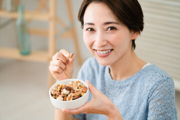 ミックスナッツを食べる若い女性　飲食イメージ