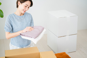 段ボールから荷物を取り出す若い女性　引っ越しイメージ	
