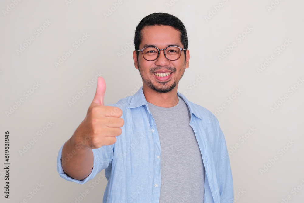 Wall mural Closeup portrait of smiling Asian man give thumb up