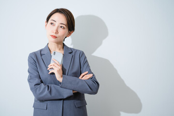 スマートフォンを持ちながら悩んでいる若い女性　ビジネスイメージ