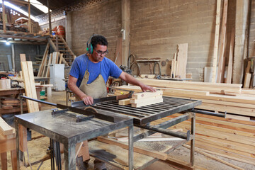 Craftsman at Work: Woodworker Using a Table Saw to Cut a Board in a Woodworking Studio