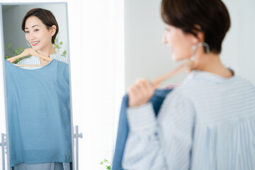 鏡の前で服選びをしている若い女性　ファッションイメージ