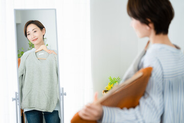 鏡の前で服選びをしている若い女性　ファッションイメージ