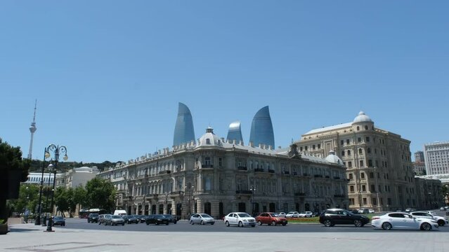 Baku, Azerbaijan - June 26, 2023: Video capturing the view of the Soviet-era building housing the office of SOCAR and the iconic Flame Towers from Azneft Square, amid flowing city traffic