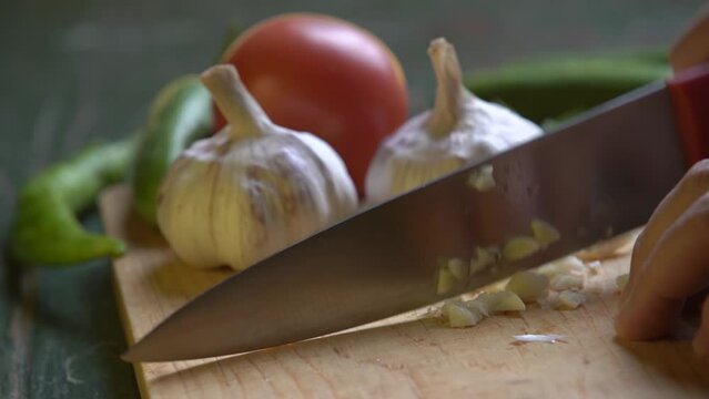 fresh garlic finely chopped with a knife on a wooden board