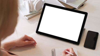 Video conference. Virtual meeting. Business woman working on project at tablet with empty space white mockup screen writing instructions at home office.