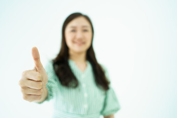 Happy cheerful Asian young adult woman showing thumb up and smiles to camera, Asian woman in action portrait on white background.