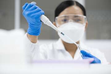 Selective focus woman scientist wearing blue gloves hand holding and using pipette drop reagent for...